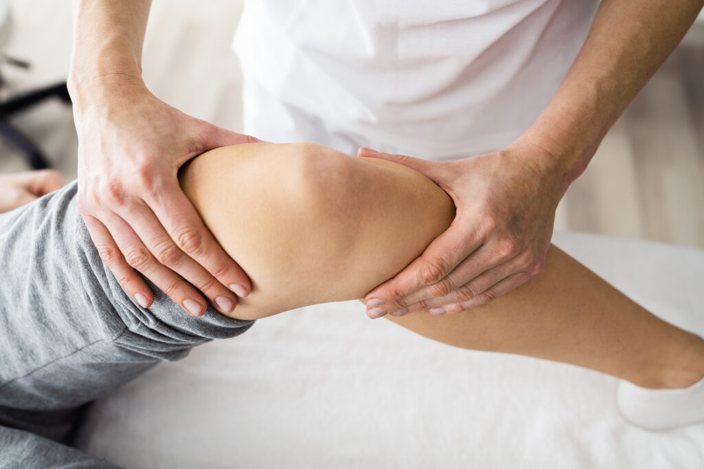 Fysiotherapeut die voelt aan de knie van een cliƫnt