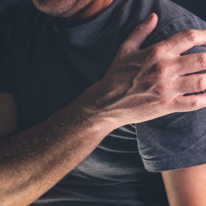 Man met frozen shoulder klachten voelt aan schouder