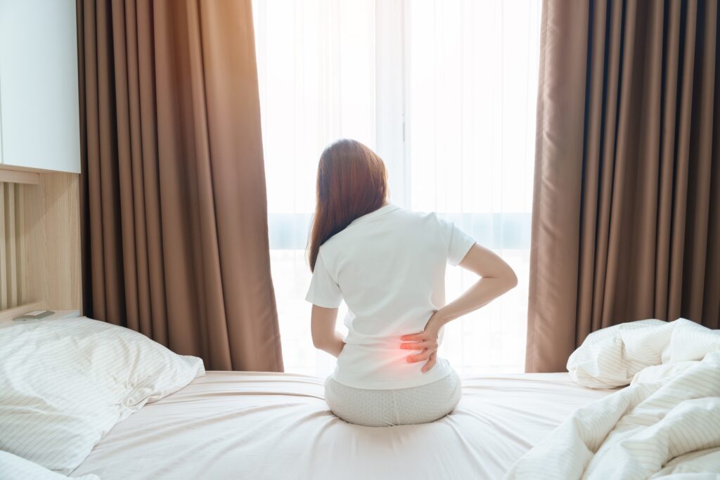 Vrouw met lage rugklachten die zit op bed