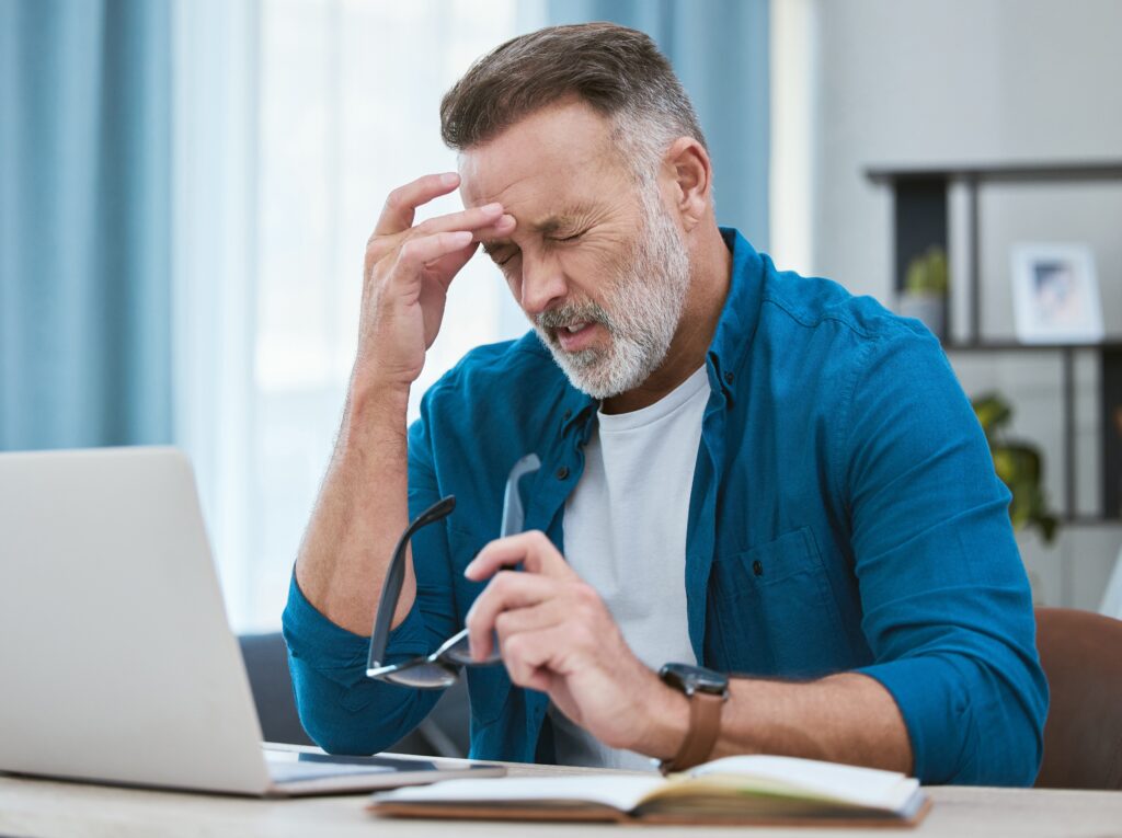 Man aan het werk achter laptop met hoofdpijn