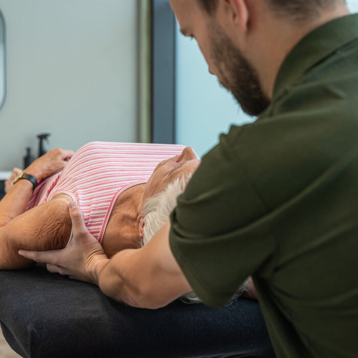 Patiënt ligt op de behandeltafel en wordt geholpen aan haar schouderpijn
